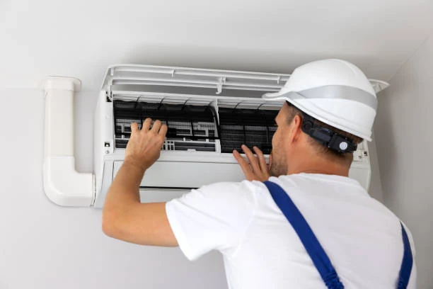 Technician removing filters from a wall-mounted air conditioning unit