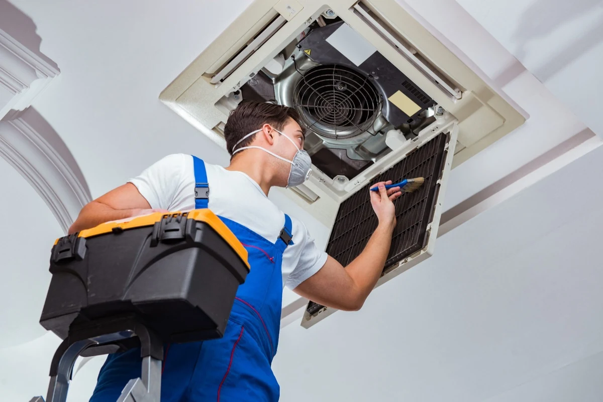 Technician servicing a ceiling-mounted air conditioning unit